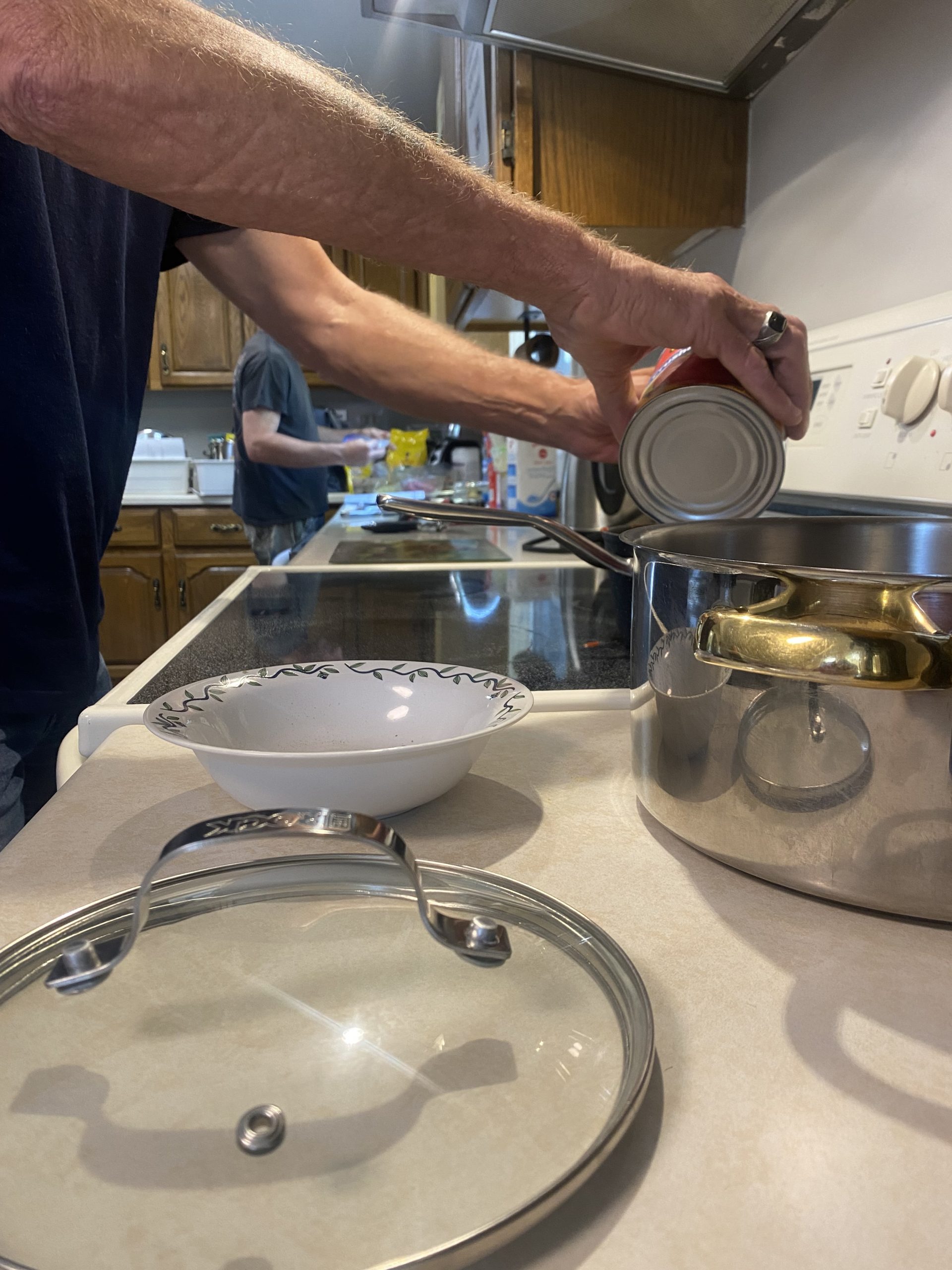 A Light House resident emptying the contents of a can into a pot during a cooking class.